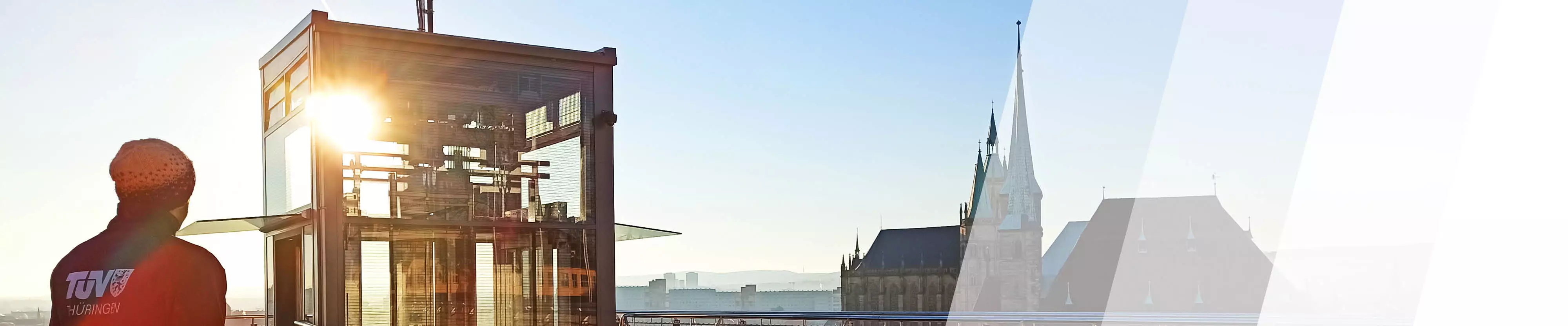 TÜV Prüfer vor einem Glasaufzug im Hintergrund der Erfurter Dom