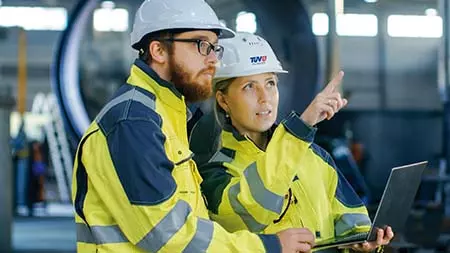 Sachverständige (Frau und Mann) mit Helm inspizieren technische Anlage