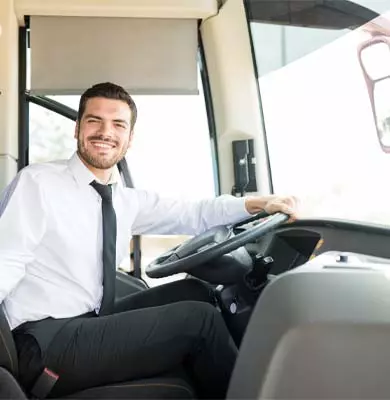 Ein Mann mit Hemd und Krawatte sitzt am Steuer eines Busses