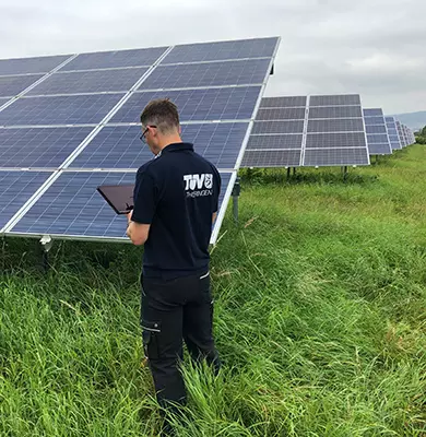 TÜV Sachverständiger mit Tablet prüft eine PV Anlage