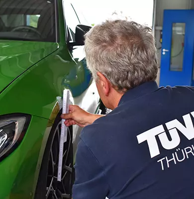 Ein Kfz-Sachverständiger misst einen Abstand am Vorderrad eines Fahrzeugs