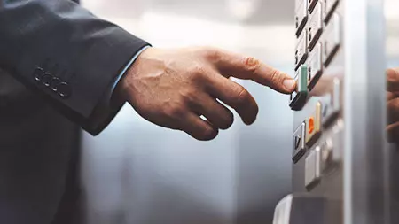 Mann drückt Taste im Aufzug