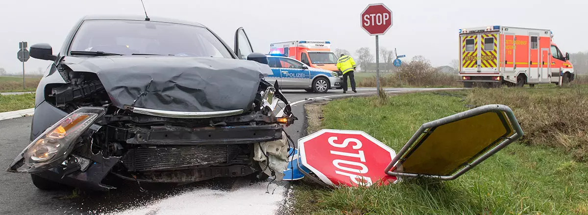 verunfalltes Auto, das ein Stoppschild überfahren hat
