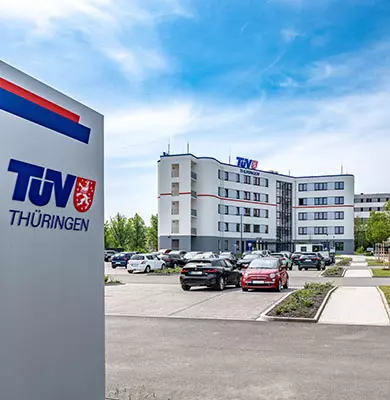 TÜV Thüringen Logo-Stele im Hintergrund TÜV Thüringen Gebäude