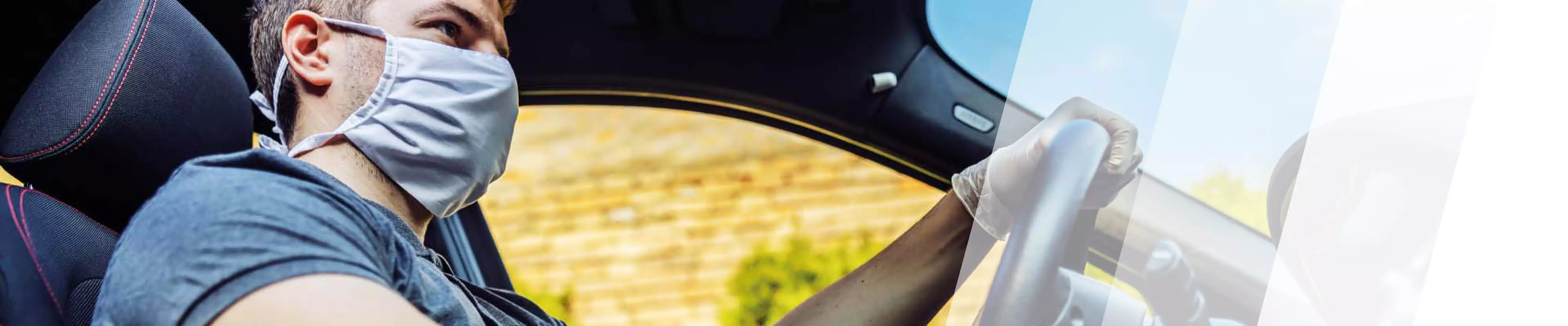 Mann mit Mundschutz fährt im Auto