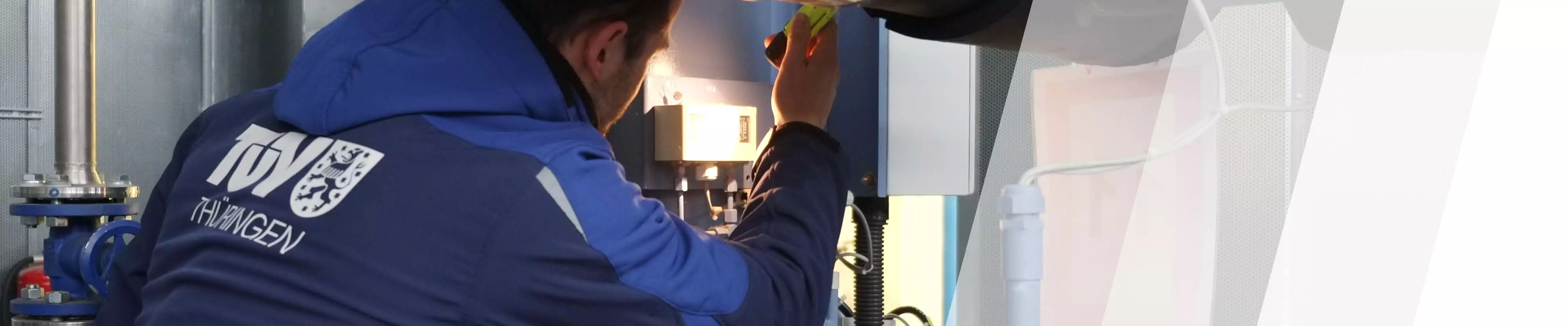 TÜV Thüringen Sachverständiger prüft leuchtet mit einer Lampe ein Druckbauteil an